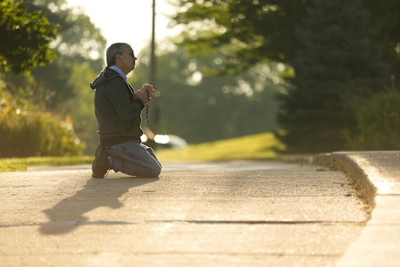 Tim Barr prays near the school on Thursday.