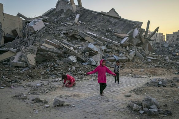 Palestinian children play next to a building destroyed by Israeli army strikes in the central Gaza Strip town of Khan Younis, Wednesday, Jan. 1, 2025.