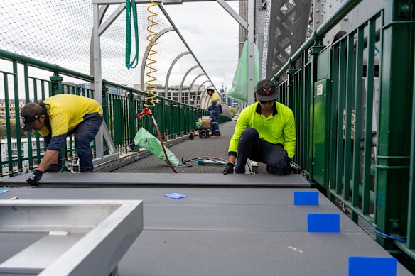 Workers repair one of the bridge’s  footpaths. 