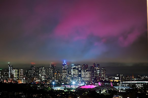 Light pollution over the Melbourne city skyline. Pink light from Marvel Stadium reflects off low clouds.