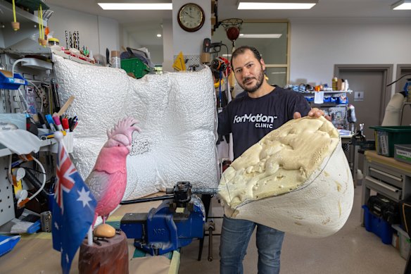 Samer Zakhour with two moulds made for Australian paralympic hopefuls. Also pictured is an Australian flag and pink cockatoo that a friend bought Zakhour when he received Australian citizenship.