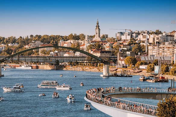 A modern pedestrian bridge, extending over the Sava River, provides a contrast to the old town of Belgrade, Serbia.