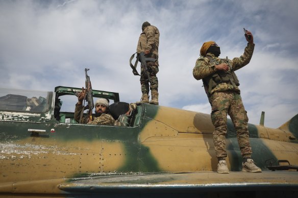 A Syrian opposition fighter holds up a mobile phone atop a seized Syrian airforce fighter plane at the Hama military airport on Friday.