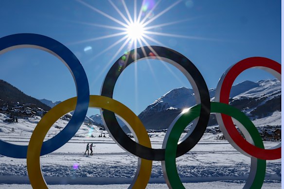 Skiiers get to work behind the Olympic rings.