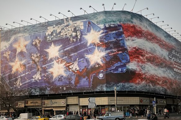 A billboard depicting a damaged US aircraft carrier with disabled fighter jets on its deck and a sign reading in Farsi and English “If you sow the wind, you’ll reap the whirlwind” in Enqelab-e-Eslami Square in Tehran, Iran, on Sunday,