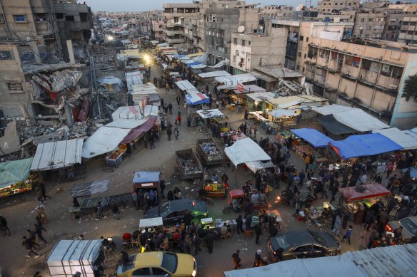 Palestinians walk along a street market in Khan Younis, central Gaza Strip,