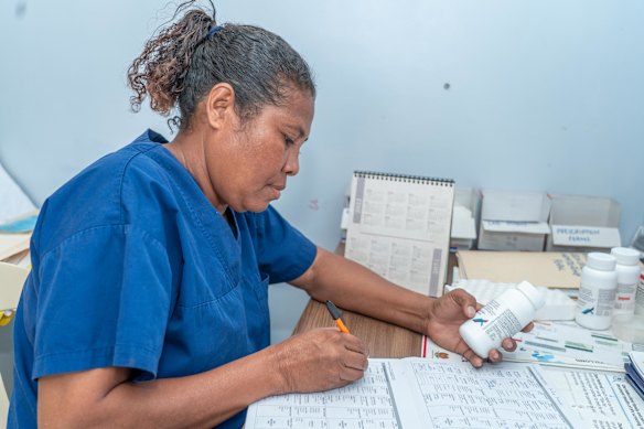 A healthcare worker in Papua New Guinea reviews clients before supplying antiretroviral therapy.