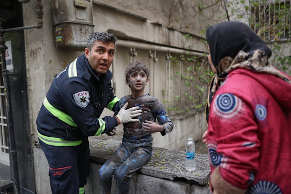 A first responder assists an injured boy following a strike that hit a residential building in Tehran.
