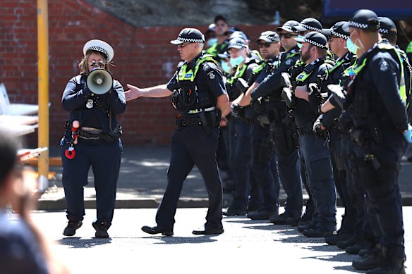 A protester dressed as a police officer is ushered away by Police during protests of Israeli President Isaac Herzog’s visit to Melbourne.