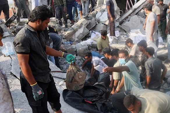 A man holds a children’s backpack as rescue workers and residents search through the rubble in the aftermath of an Israeli-US strike on what Iranian officials said was on a girls’ elementary school in Minab, Iran.