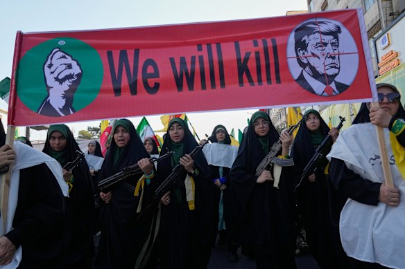 Women march beneath a banner depicting US President Donald Trump in crosshairs.
