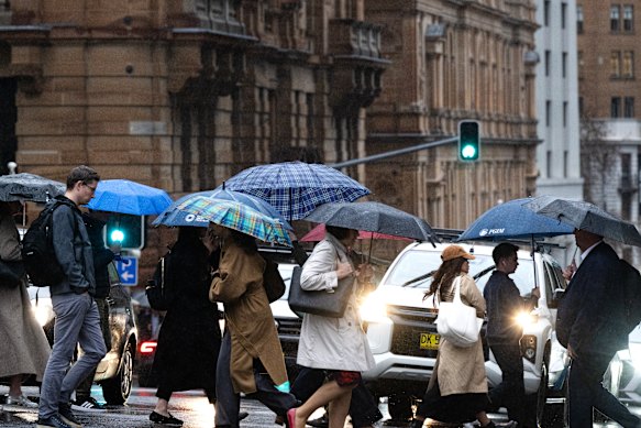 People crossing a Sydney CBD street in the rain on Thursday.
