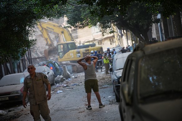 A man watches an excavator remove debris at the site of an Israeli airstrike in Beirut on Wednesday.