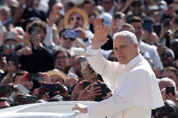 Pope Leo XIV waves as he arrives ahead of his inauguration mass.