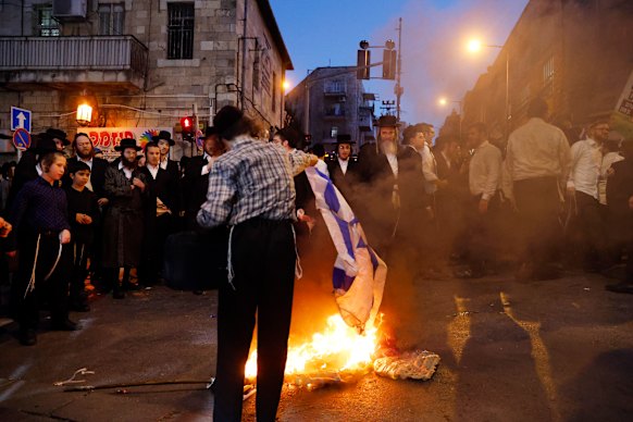 An ultra-Orthodox Jew burns an Israeli flag as anti-government amid protests against their military service exemptions.