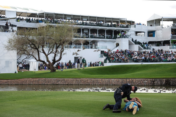 A fan dressed in costume as William Wallace from Braveheart, is apprehended by a police officer after running on the 11th hole.