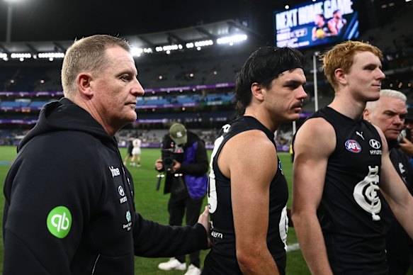 Carlton coach Michael Voss and Elijah Hollands (centre) leave the field on Thursday night.