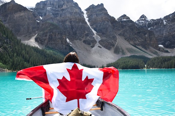A young girl in a canoe holds a Canadian flag in Lake Moraine, in Banff National Park, Alberta, Canada.