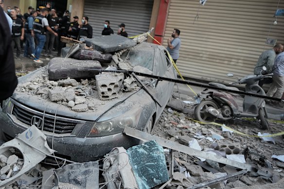 Security officers gather near destroyed vehicles at the site where an Israeli strike hit at an apartment building in Dahiyeh, Beirut.