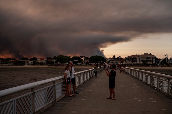 People pose on the beach in Andernos-Les Bains during a fire in Lege Cap-Ferret forest, in southwestern France.