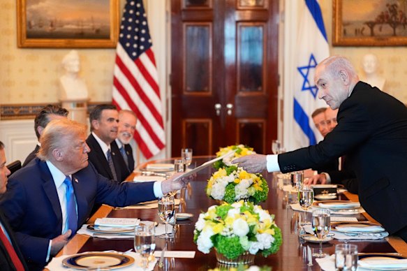 Israel’s Prime Minister Benjamin Netanyahu, right, hands US President Donald Trump a folder during a meeting in the Blue Room of the White House on Monday.