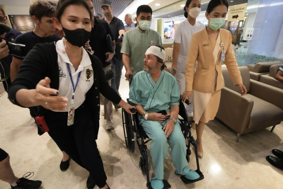 Keith Davis (centre) is whisked away and prevented from talking to reporters at Samitivej Srinakarin Hospital in Bangkok, Thailand.