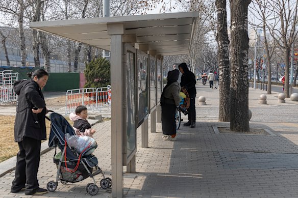 People read copies of Chinese state media newspapers posted at a public newsstand in Beijing.