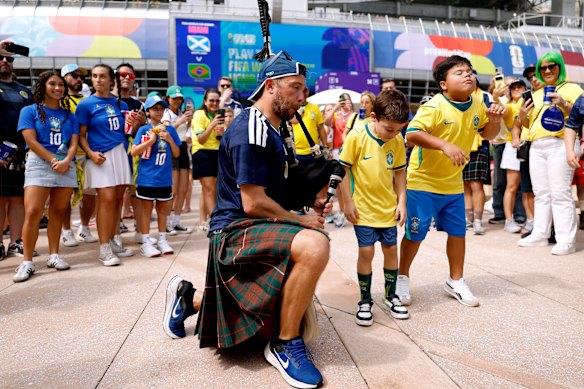 A Scotland fan playing the bagpipe for young Brazilian fans, ahead of their match in Miami.