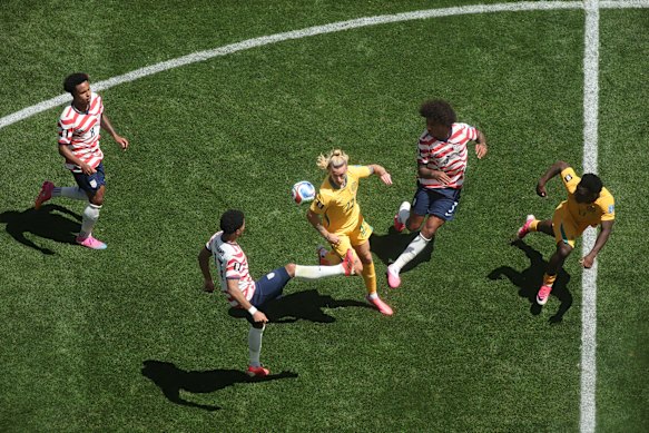 Surrounded by USA opponents, Jackson Irvine competes for the ball.