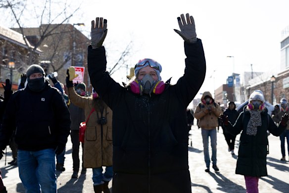 Protesters advance towards federal agents with their hands up near the site of the fatal shooting of Alex Pretti.