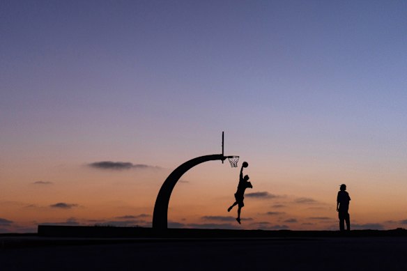 People play basketball in a park at dusk in the San Pedro neighborhood of Los Angeles.