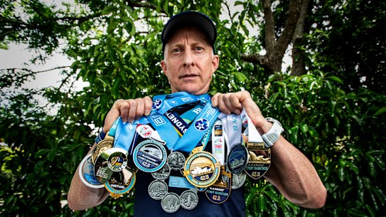 Mark Goodwin with his medals from years of competing in the Sydney Marathon, and his medal for finishing every major in the world.