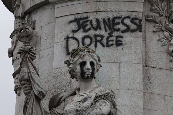 A graffiti tag reading “the golden youth” adorns the iconic statue of Equality in Paris’ Place de la Republique.