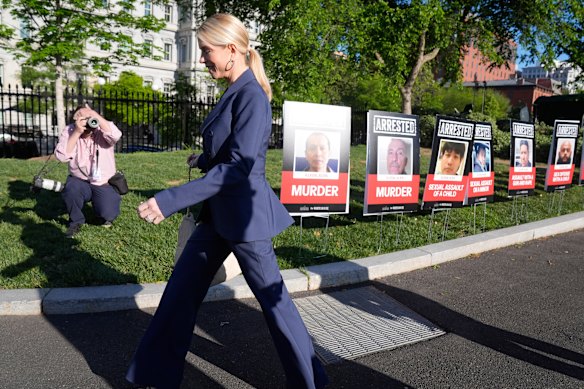 US Attorney-General Pam Bondi walks past the row of “ARRESTED” yard signs at the White House.