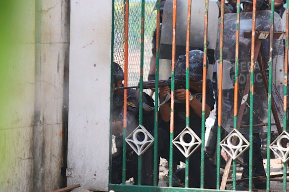 A police officer aims his weapon at protesters on Monday.