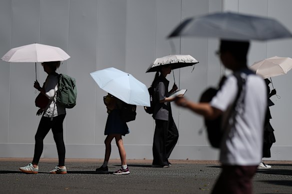 People use umbrellas to shield themselves from the scorching sun in Tokyo.