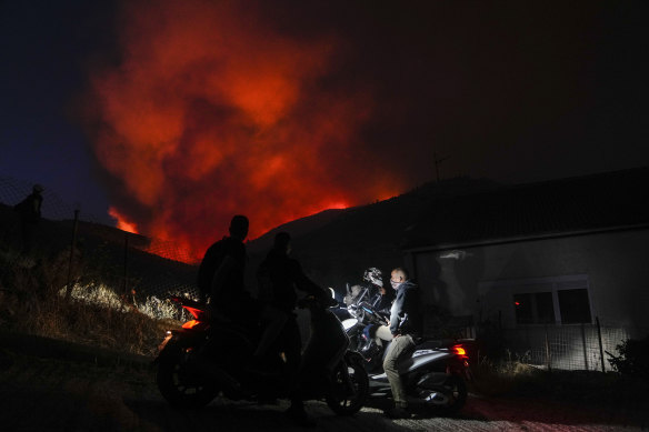Men on motorbikes watch a fire in Penteli, Greece, in July.