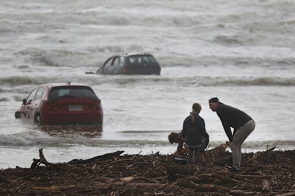 Families trying to recover belongings after they were swept away in a deluge of rain into the ocean, including several cars.