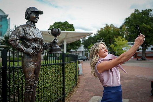 A smiling Michelle Payne takes a selfie with her new statue at Flemington.