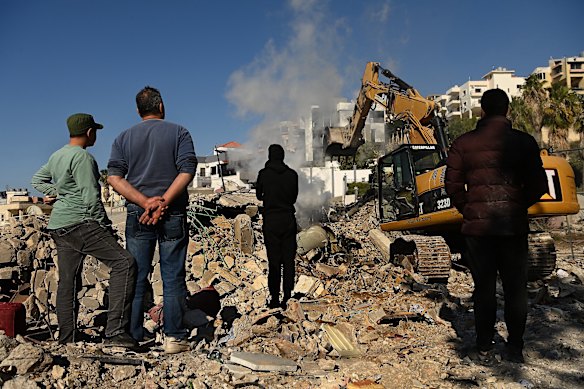 Local authorities stand amongst the debris following an Israeli airstrike in Ghaziyeh on March 8.