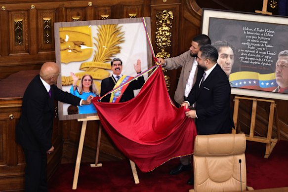 Nicol&aacute;s Maduro Guerra and Yosser Gavidia Flores, son of Cilia Flores, unveil a picture of their parents at the National Assembly on Monday.