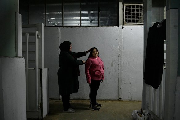 A woman brushes her daughter&rsquo;s hair near the amenities area at a shelter.