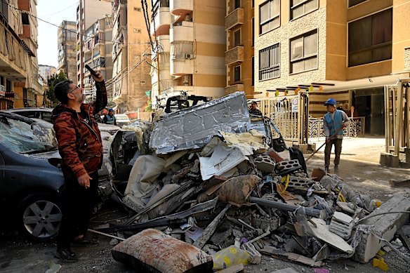 A man takes a photo of a damaged apartment building in Aisha Bakkar. 