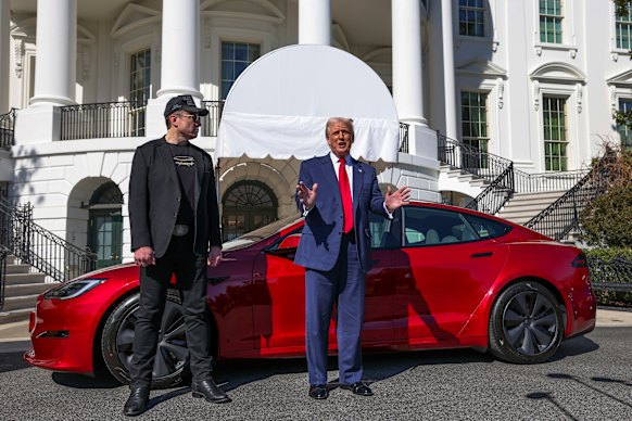 Trump and Musk speak to reporters in front of a red Model S Tesla at the White House in March.