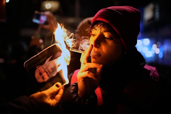 A protester smokes a cigarette after lighting it off a burning picture of Iran’s Supreme Leader Ayatollah Ali Khamenei during a demonstration in Berlin last Wednesday.