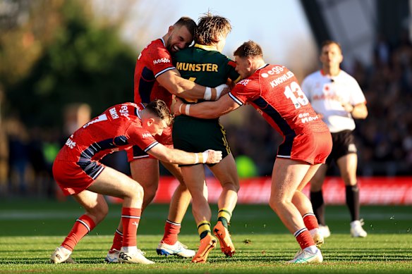 Cameron Munster is tackled by England’s Harry Smith, Mike McMeeken and Morgan Knowles.