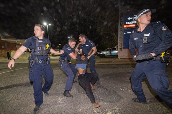 Officers pull a protester across a road outside the hospital.
