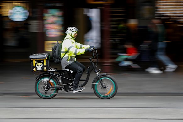 A food delivery driver rides an e-bike along Swanston Street. There is no suggestion this bike does not comply with regulations. 