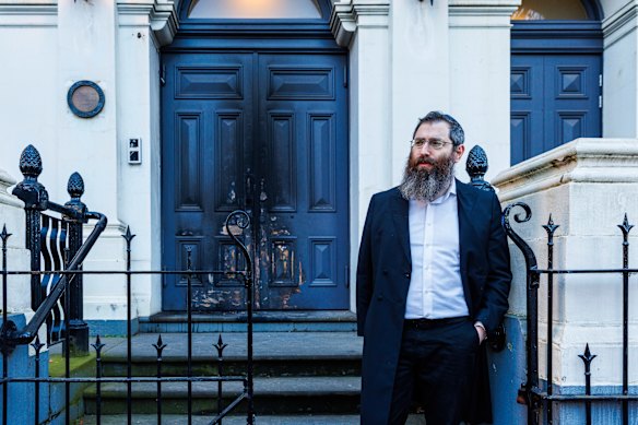 Rabbi Dovid Gutnick stands in front of the charred entrance to the East Melbourne Synagogue.