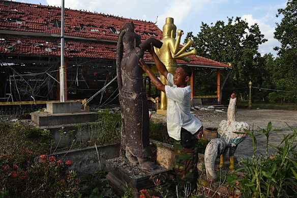Prum Chenda, deputy chief of the local Achar, holds a section of a statue at the destroyed Ta Moan Sen Chet Pagoda.